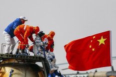 Chinese astronaut Wang Yaping (2nd R) waves as she is assisted by officials to leave the capsule of the Shenzhou-13 spacecraft after landing in China's Inner Mongolia on April 16, 2022.