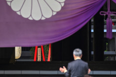 A man prays in front of a wooden plaque showing the name of Japan's Prime Minister Fumio Kishida seen with a 