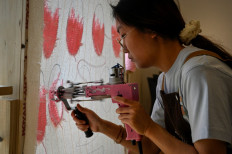 This photo taken on April 2, 2022 shows a staff member using a craft gun to create patterns on stretched fabric at a tufting workshop in Beijing.