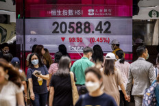 People walk past a display showing the Hang Seng Index in Hong Kong, China, on April 22, 2022.