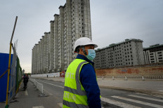 A worker prepares to cross a street outside a construction site in Beijing on April 26, 2022.