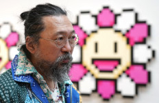 Artist Takashi Murakami stands in front of 'Murakami.Flower Pink & White, 2000' during a press preview May 11, 2022 for 'An Arrow through History' at Gagosian’s New York galleries.
