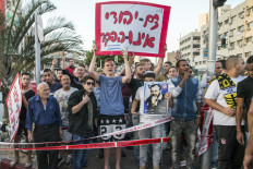Israeli far-right demonstators hold a placard that reads in Hebrew "The Jewish blood will not be abandoned" and a poster of late Brooklyn-born Rabbi and founder of Jewish anti-Arab movement Meir Kahane, at the scene of a stabbing attack in the Israeli city Rishon LeZion, about 10km (six miles) south of Tel Aviv on November 2, 2015. A Palestinian stabbed and wounded three Israelis near Tel Aviv before being arrested, Israeli police said, the latest in a series of such attacks. 