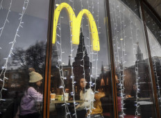 People look out of the window of a McDonald's restaurant as the towers of the Kremlin reflect in it in Moscow on January 30, 2020.