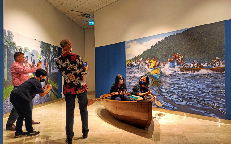 Selfie op: Visitors take pictures as they sit in a 'kora-kora', the traditional canoe of the Banda Islands, surrounded by Isabella Boon’s photographs of daily life in the island chain. The canoe was made especially for Boon’s “I Love Banda” photography and multimedia exhibit, which runs through June 17, 2022 at Erasmus Huis Jakarta. (JP/Sylviana Hamdani)