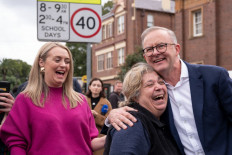 Opposition Labor Party leader Anthony Albanese (R) is greeted by a supporter as his partner Jodie Haydon (L) looks on during Australia's general election at a polling station in the suburb of Marrickville in Sydney on May 21, 2022. 