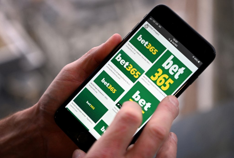 Betting market: A man poses for a photograph with the logo for online gambling website Bet365 displayed on a smartphone on Dec. 18, 2019.