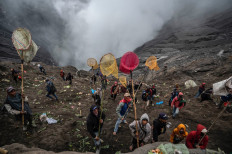 Villagers use nets to catch offerings thrown by members of the Tengger sub-ethnic group in the crater of the active Mount Bromo volcano as part of the Yadnya Kasada festival in Probolinggo, East Java province on June 16, 2022. 