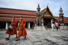 In this file photo taken on November 2, 2021, Buddhist monks wearing face masks walk inside the Grand Palace, a day after Thailand welcomed the first travellers vaccinated against the Covid-19 coronavirus, in Bangkok.