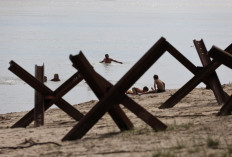 Swimmers bathe in the Danube river next to anti-tank obstacles on the beach near Izmail, in the Odessa region on June 14, 2022, amid the Russian invasion of Ukraine.