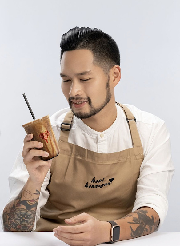 Carving paths: Mikael Jasin poses with a coffee beverage in an apron bearing the logo of Indonesian coffee specialist and chain Kopi Kenangan, where he is the head of coffee. (Instagram/Mikael Jasin)