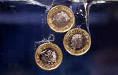 Pound coins plunge into water in this illustration photo taken on May 23, 2022.

