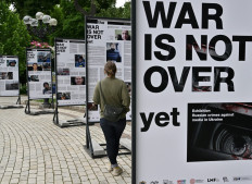 A woman visits the photo exhibition 'The war is not over"' opened in the Taras Shevchenko park in Kyiv on June 23, 2022, amid Russia invasion of Ukraine. 