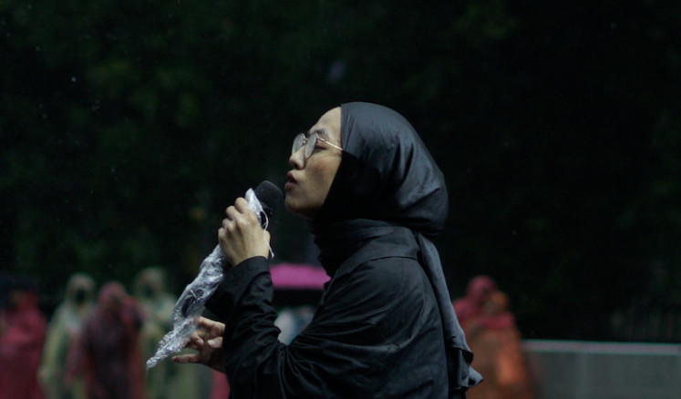 Fitting background: Folk artist Feby Putri performs during heavy rain on June 24, the first of the inaugural Swaraya music festival at the Bogor Botanical Gardens, many of her songs taken from her debut album, ‘Riuh’ (Tumultuous), released in January. (Courtesy of Swaraya)