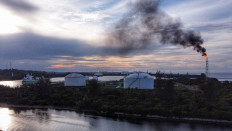 A flare tower emitting flames and smoke is seen from a Perta Arun Gas facility in Lhokseumawe, Aceh, on Oct. 18, 2021.