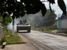 Ukrainian soldiers ride an armoured vehicle on the main road to Lysychansk in Ukraine’s eastern region of Donbas on June 26, 2022. Russian forces achieved major military successes in eastern Ukraine on June 25, 2022, fully capturing the strategic city of Severodonetsk after a fierce battle and entering the nearby city of Lyssychansk, as the conflict entered its fifth month.