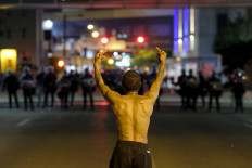 A man gestures toward troopers in riot gear as police deployed tear gas and stun grenades to clear the area around Akron City Hall and Akron Police Station during a protest over the killing of Jayland Walker, shot by police, in Akron, Ohio, July 3, 2022. Several hundred protesters marched Sunday in Akron, Ohio after the release of body camera footage that showed police fatally shooting a Black man with several dozen rounds of bullets.