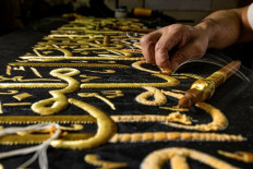 An embroiderer sews with gold thread a verse from the Holy Koran, Islam's holy book, onto a replica of the Kiswa, the cloth used to cover the Kaaba at the Grand Mosque in the Muslim holy city of Mecca, to be sold as a souvenir for tourists visiting the historic district of al-Hussein of Islamic Cairo in Egypt's capital on June 15, 2022. From the 13th century, Egyptian artisans made the giant cloth in sections, which authorities transported to Mecca with great ceremony. Celebrations would mark processions through cities, flanked by guards and clergymen as Egyptians sprinkled rosewater from balconies above. From 1927, manufacturing began to move to Mecca in the nascent Kingdom of Saudi Arabia, which would fully take over production of the kiswa in 1962.
