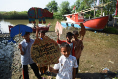Children hold cardboard puppets and a poster that reads “Save Indonesia’s forests” during a show about animal conservation by former teacher Samsudin, in this file photo taken recently.