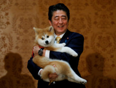 In this file photo, Japanese Prime Minister Shinzo Abe poses with an Akita Inu puppy presented to Russian figure skating gold medallist Alina Zagitova, in Moscow, Russia May 26, 2018.