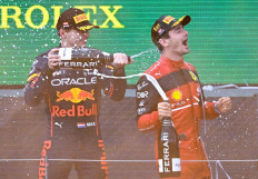 Second placed Red Bull Racing's Dutch driver Max Verstappen (L) and winner Ferrari's Monegasque driver Charles Leclerc celebrate on the podium with champagne after the Formula One Austrian Grand Prix at the Red Bull Ring race track in Spielberg, Austria, on July 10, 2022.  