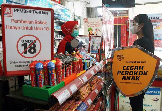 Smokescreen: A volunteer talks to a minimarket cashier about the dangers of cigarettes during a campaign against child smokers in Cengkareng, West Jakarta on March 7, 2021. The campaign aims to accelerate the government’s target to reduce child smokers to 8.7 percent of the smoking population in 2024.