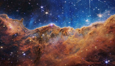 An image captured by the James Webb Space Telescope (JWST) shows a landscape of “mountains” and “valleys” speckled with glittering stars, which is actually the edge of a nearby, young, star-forming region called NGC 3324 in the Carina Nebula.