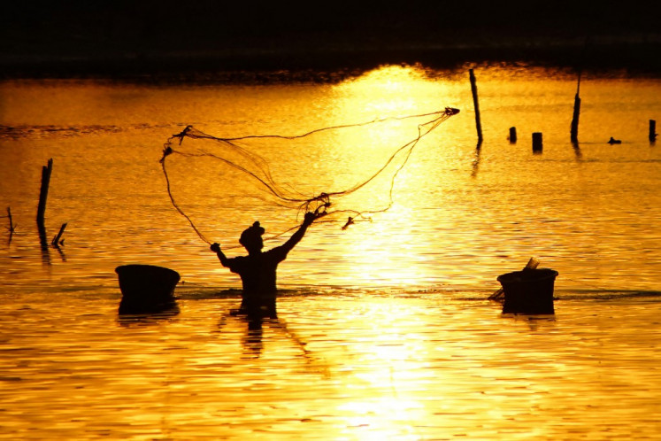 A fisherman casts a net at sunset at Cunda estuary in Lhokseumawe, Aceh, on July 15, 2022.
