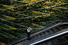 A man wearing a protective mask rides an escalator at a business building in Tokyo.