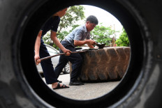 This photo taken on July 8, 2022 shows workers cutting apart a rubber truck tyre outside a workshop in Hanoi.