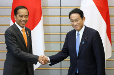 Japanese Prime Minister Fumio Kishida (right) shakes hands with President Joko 'Jokowi' Widodo prior to their talks at the prime minister's office in Tokyo on July 27, 2022.

