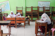 A small group of students sit in class surrounded by upturned chairs at State Elementary School 5 Cikidang in Lembang, West Java on July 26, 2022. For the past two years, the school does not have enough students enrolled due to it being situated far from residential areas in West Bandung regency. There are a total of 47 students in grades 3 to 6 and just two teachers at the school.