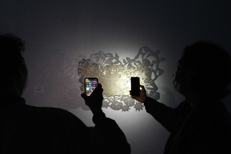 Art enthusiasts: Exhibition attendees use flashlights from their handphones to accentuate the cowhide carving by Gede Sukarya. (Courtesy of Gurat Institute)