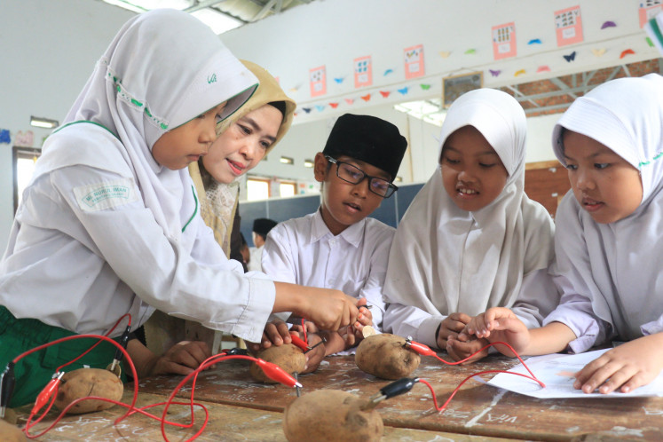 School activities: Pictured is a teacher and three students in a class at Madrasah Ibtidayah Nurul Iman, one of Tanoto Foundation's partner schools in Muaro Jambi, Jambi. (Courteys of Tanoto Foundation)