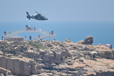 Tourists look on as a Chinese military helicopter flies past Pingtan island, one of mainland China's closest points from Taiwan, in Fujian province on Aug 4, ahead of its massive military drills off Taiwan following United States House Speaker Nancy Pelosi's visit to the self-ruled island.
