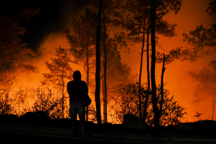 A resident stands near a forest fire on Aug. 7, 2022, in Simulop village, Panguruan district, Samosir regency, North Sumatra.