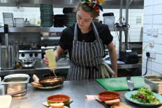 A member of staff prepares some food at The Canteen restaurant, one of the first in the UK to place the carbon footprint of its dishes on its menu besides the calories, in Bristol, on August 3, 2022. The Canteen became in July the first restaurant to agree to put its carbon footprint on the menu under a campaign spearheaded by UK vegan campaigning charity Viva!

