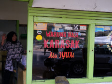 A welcoming face: Shopkeeper Etty poses at her eatery, Warung Nasi Karasak Ma Iyum, in Bandung, West Java, in August.