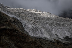 Low clouds drift over the Swiss Alps behind the melting Fee Glacier on July 30, 2022, located above the Saas-Fee alpine resort area.