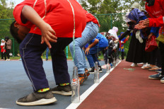 Indonesian children partake in a classic game of nail-in-a-bottle at the Islamic University of Malaysia’s sports complex in Kuala Lumpur, on Aug. 14, just days before Indonesia’s 77th Independence Day. The aim of the game is to lower a nail into an empty bottle using only a string that is attached to a participant’s body.