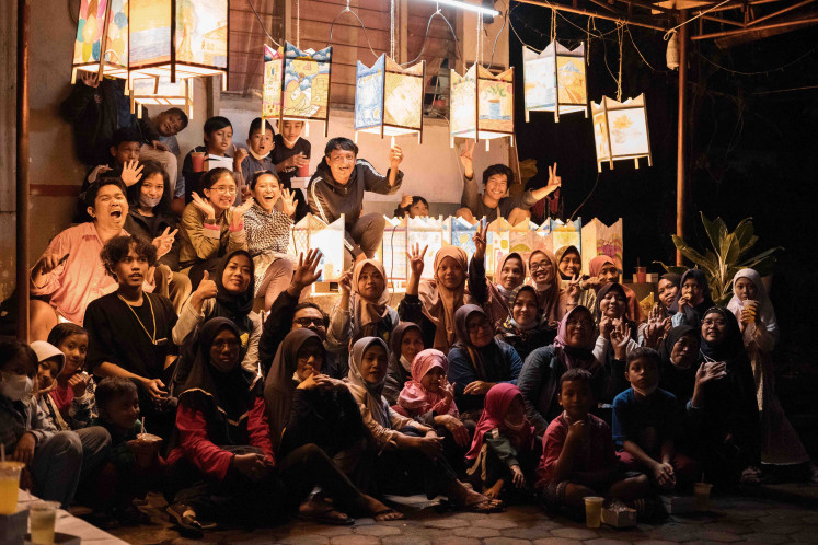 Bright celebration: Novan Effendy (center rear, in black top) and the residents of Cibogo, Sukawarna village, Bandung, gesture during the Sariak Layung Damar Kurung parade on April 6, 2022 to mark the start of Ramadan. (Courtesy Rakarsa Foundation)
