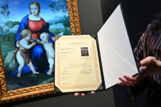 NFT art: A gallery assistant looks at a digital reproduction of the painting Madonna del Cardellino (Madonna of the Goldfinch) by Raphael, displayed on Feb. 15, 2022 in the “Eternalising Art History: From Da Vinci to Modigliani” exhibition at the Unit London gallery in London.