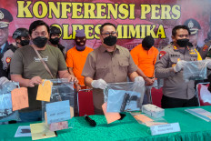 Police officers show the murder suspects (orange clothes) and evidence in Timika on Aug. 30, after six soldiers and four civilians were accused of killing and mutilating four indigenous Papuans.