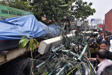 People mill around a flatbed truck and a fallen cell tower on Jl. Sultan Agung in Bekasi, West Java, on Aug. 31, 2022. The truck had plowed through a bus stop in front of an elementary school on Wednesday morning, killing 10 people and injuring at least 20 others, of whom the majority were schoolchildren, and then hitting several vehicles before toppling the tower and coming to a stop.