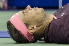 Spain's Rafael Nadal lies on the court and seeks medical attention after hitting himself in the face with his racket during his 2022 US Open Tennis tournament men's singles second round match against Italy's Fabio Fognini at the USTA Billie Jean King National Tennis Center in New York, on September 1, 2022. 
