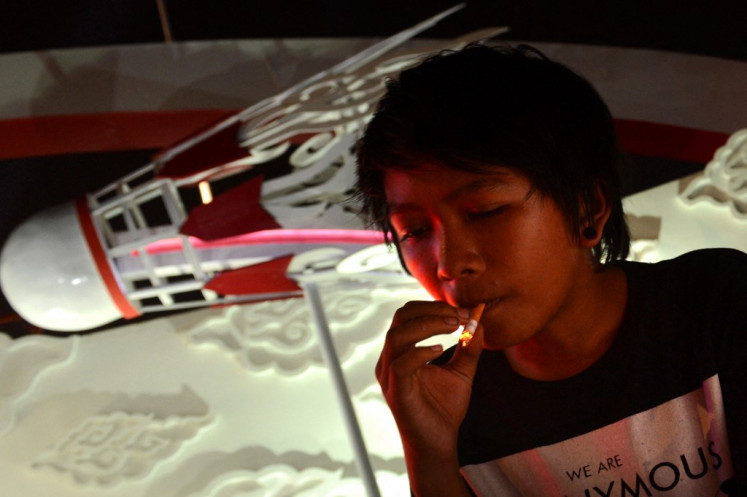 Teens and cigarettes: An Indonesian youth smokes a cigarette at the entrance of the Djarum-sponsored Indonesia Open badminton tournament at the Senayan stadium in Jakarta, on June 14, 2013. (AFP/Romeo Gacad)