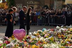 (Left-right) Meghan, Duchess of Sussex, Britain's Prince Harry, Duke of Sussex, Britain's Prince William, Prince of Wales and Britain's Catherine, Princess of Wales look at floral tributes laid by members of the public on the Long walk at Windsor Castle on September 10, 2022, before meeting well-wishers. King Charles III pledged to follow his mother's example of 