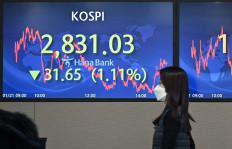 A currency dealer walks past a screen showing South Korea's benchmark stock index in a trading room at Hana Bank in Seoul on Jan. 21, 2022.