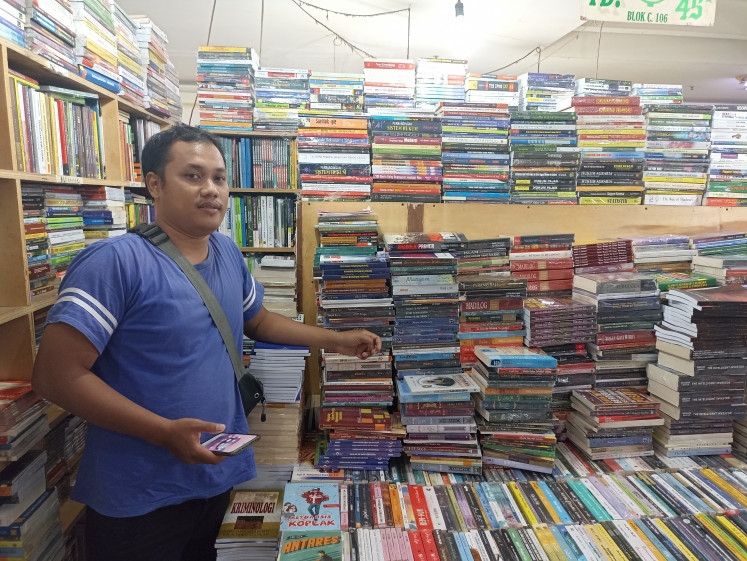 Umar Wirahadi Kusuma, owner of the Papat Limo bookstore in Blok M Square mall, South Jakarta, poses among piles of secondhand books on Sept. 8, 2022. Umar says that his revenue has dropped by around 70 percent over the last decade.