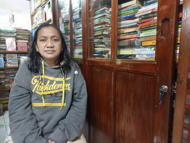 Bookshop owner Wiwik Latifah, who sells new, secondhand and rare books, poses in front of cupboards full of books in her shop in Blok M Square mall, South Jakarta on Sept. 8, 2022. Wiwik said her revenue from selling books has dropped by 50-70 percent, especially after the COVID-19 pandemic.
